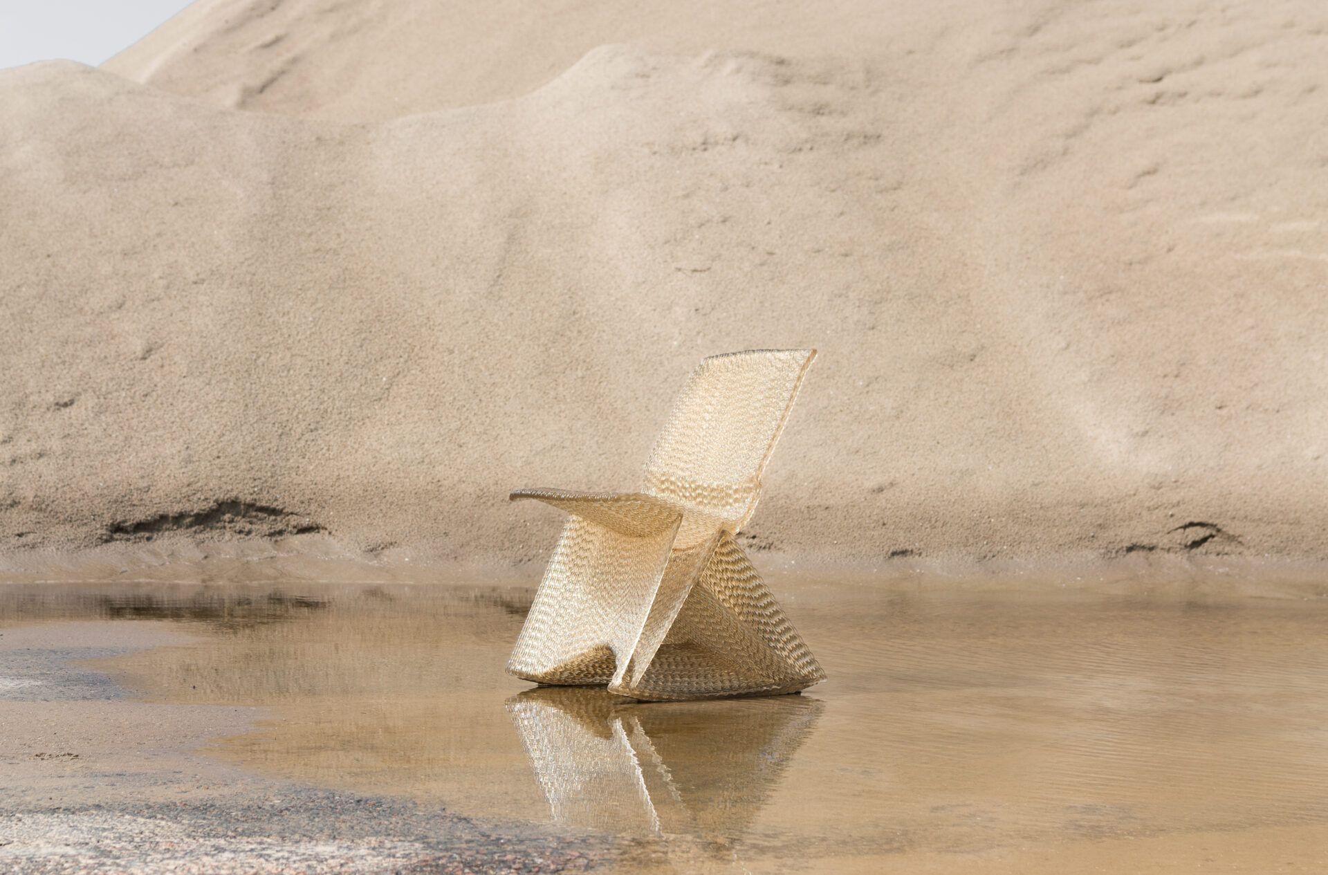 Endless Chair by Dirk van der Kooij made from recycled plastic, displayed outdoors against a sandy backdrop.