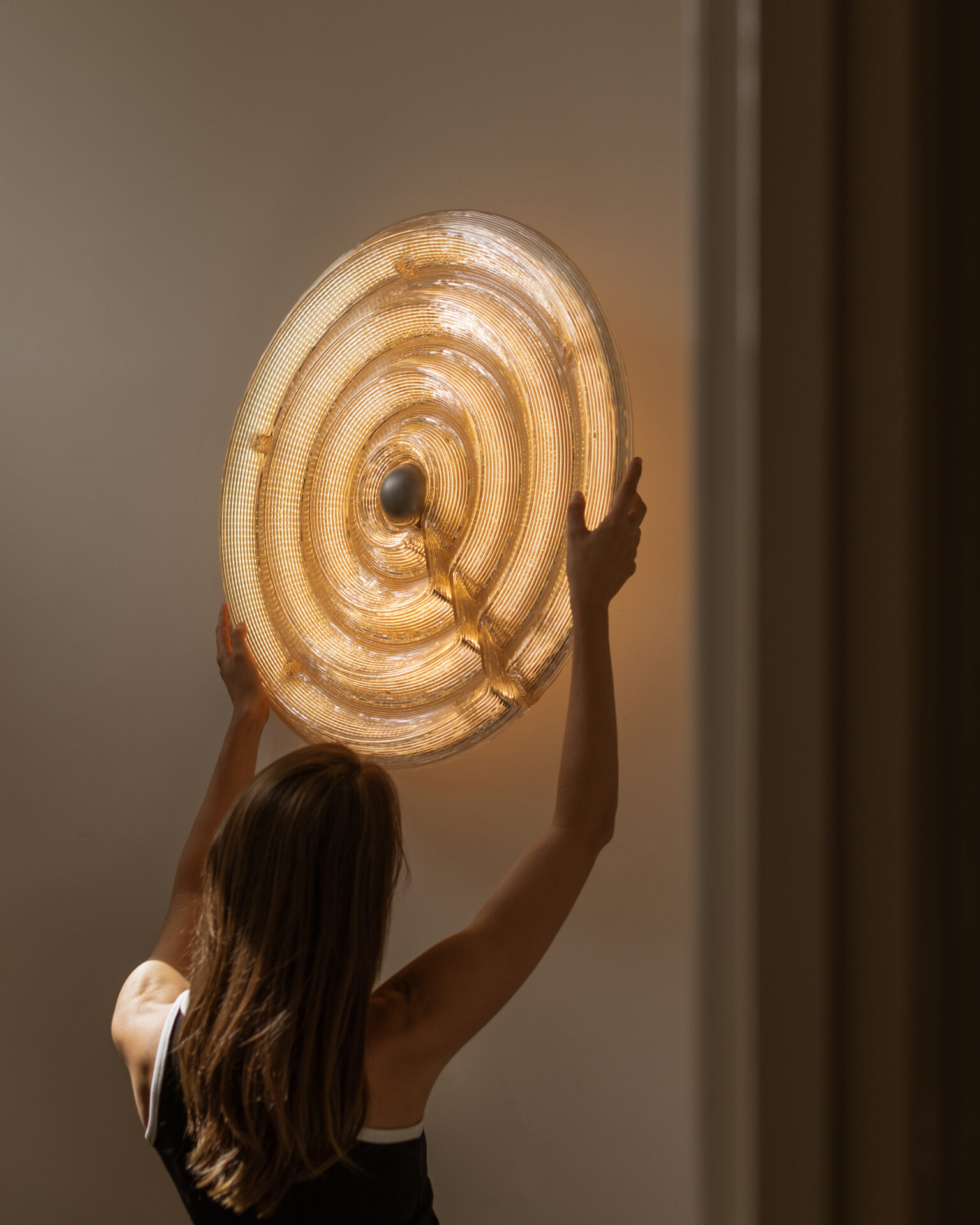 Fresnel Light by Dirk van der Kooij, circular recycled plastic wall lamp glowing with warm light.